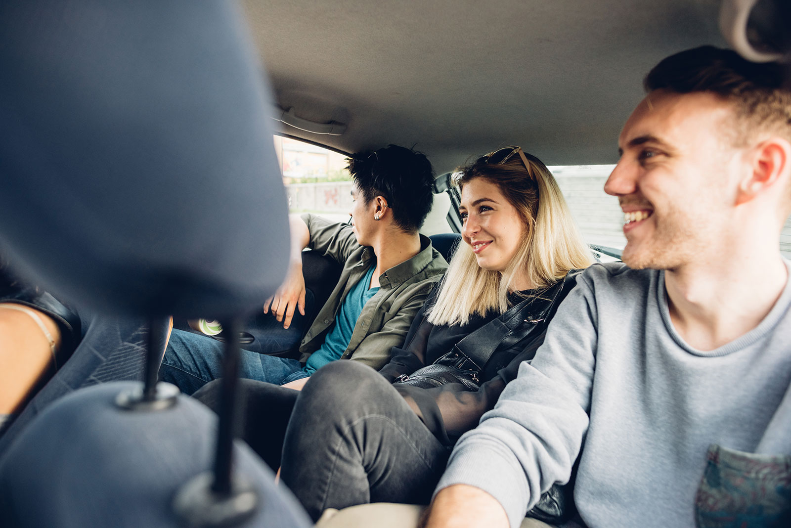 Group of three young adults riding in the backseat of a ride-share car